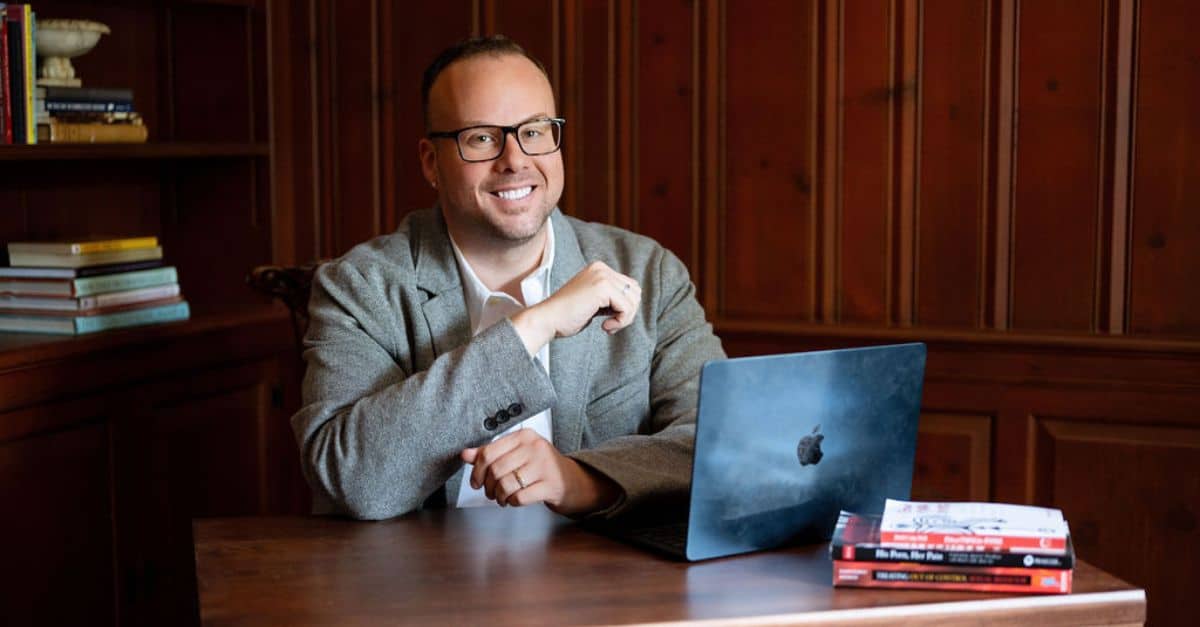 Dr. Mike sites at his desk with his laptop.