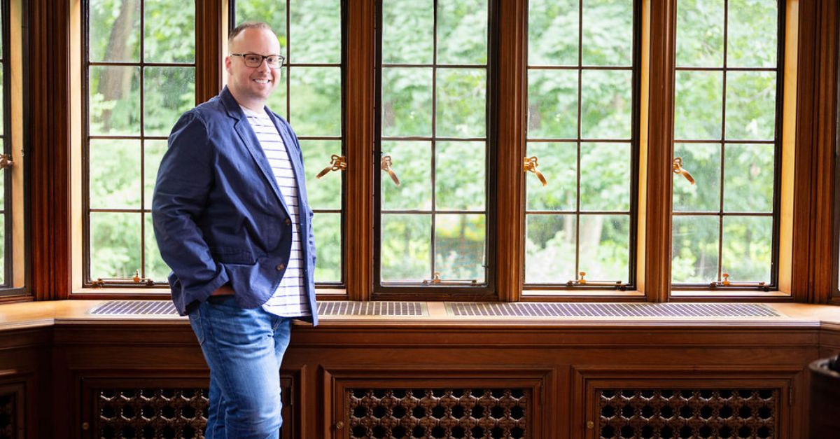 Dr. Mike stands in front of bay windows with a warm, inviting smile.