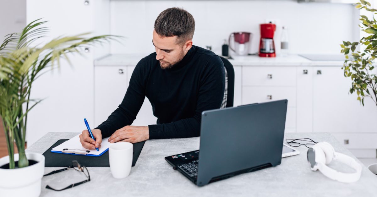 Man sits at desk and makes a list.