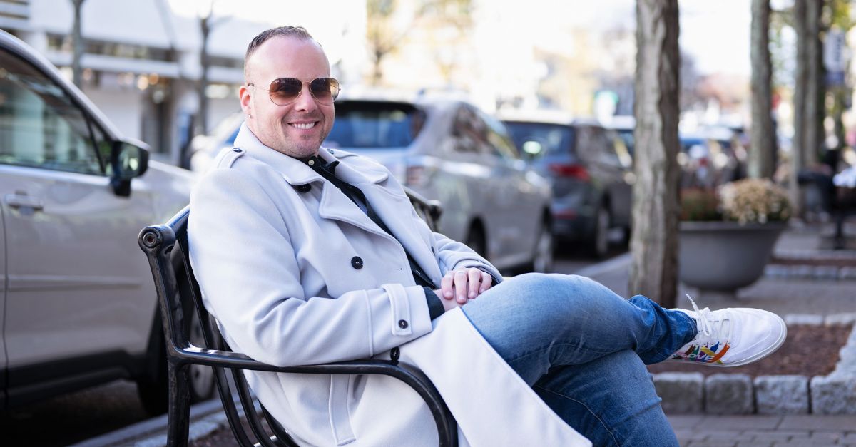 Dr. Mike sits on a bench outside smiling at the camera