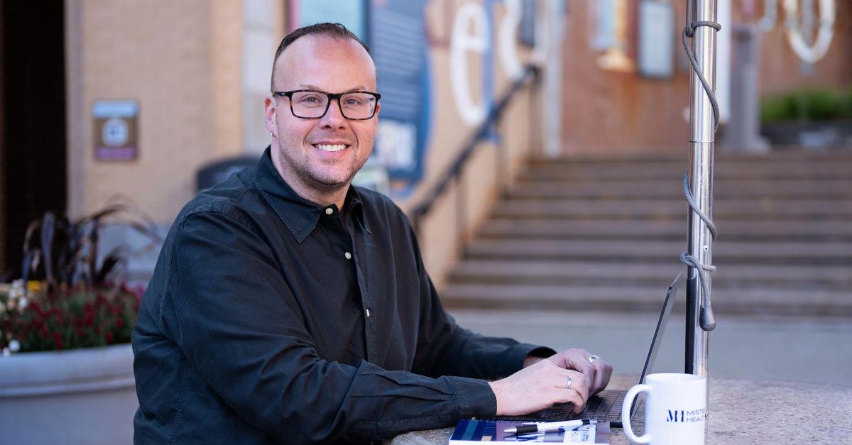 Dr. Mike smiles warmly while sitting at a table outside.