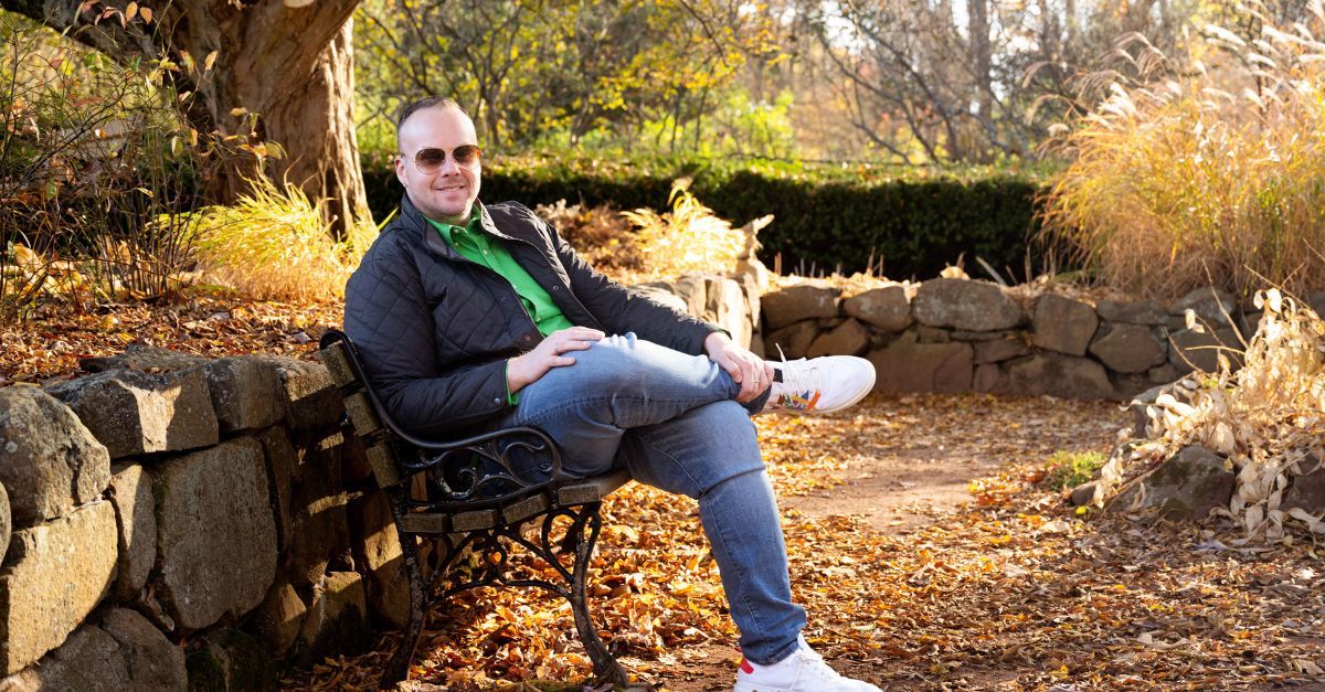 Dr. Mike Stokes sits on a park bench with a welcoming smile.