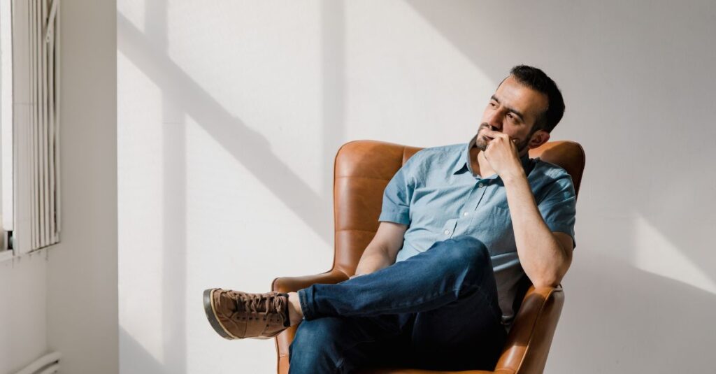 A man sits in his office chair, looking out the window, reflecting.