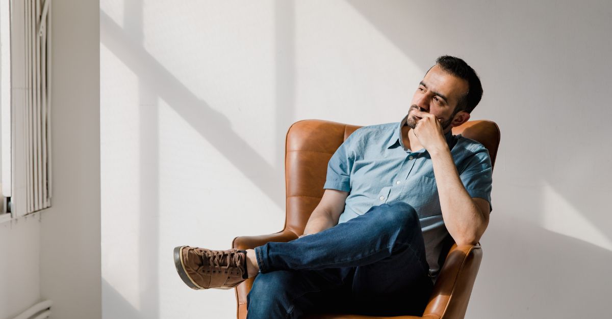A man sits in his office chair, looking out the window, reflecting.