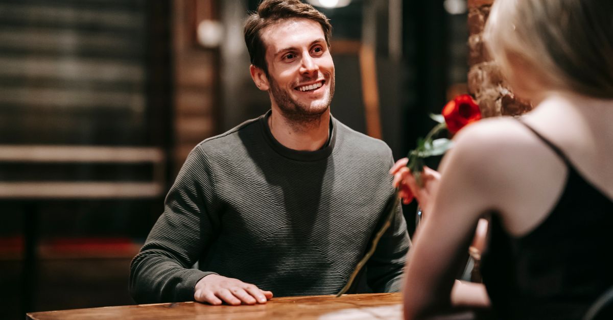 Man smiling warmly at his partner during a date night, representing connection and intimacy in relationships.