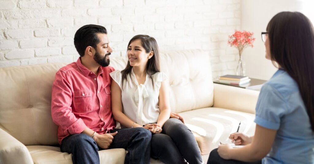 Couple sitting together in therapy, working with a counselor to strengthen communication and intimacy.