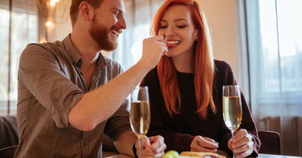 Smiling couple enjoying dinner together on date night, with champagne and playful intimacy.
