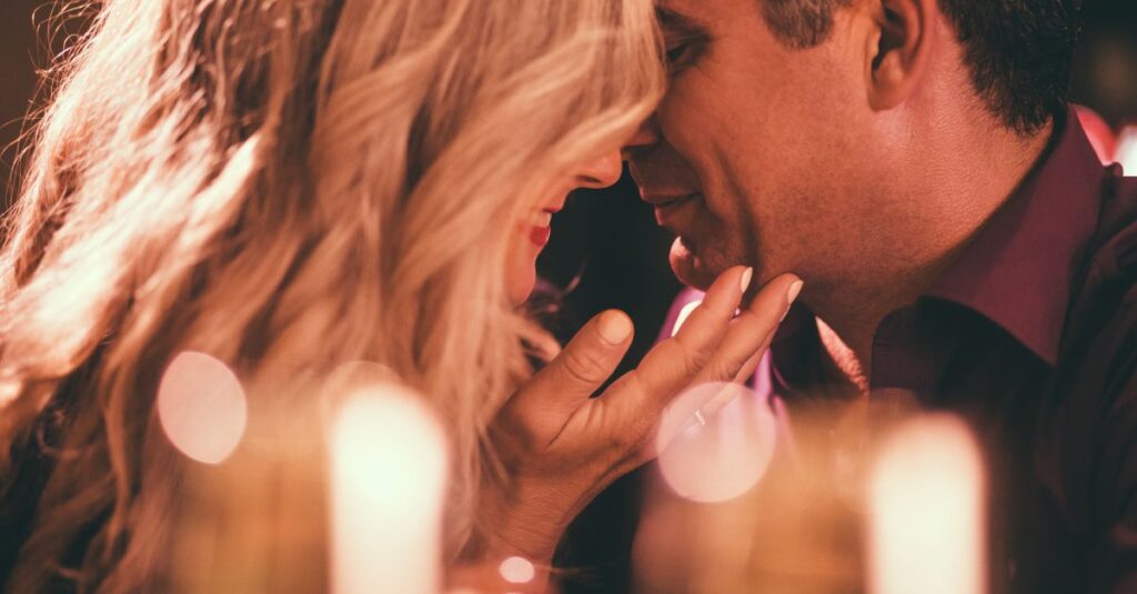Couple sharing a tender moment during a romantic date night with candlelight in the background