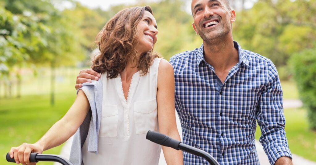 Happy couple outdoors with bicycles, smiling and enjoying each other’s company, symbolizing connection and healthy intimacy.
