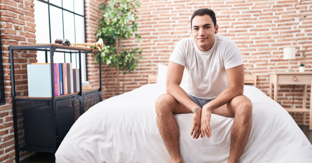 Confident man sitting on a bed in soft natural light, symbolizing calm, self-assured energy and emotional balance.
