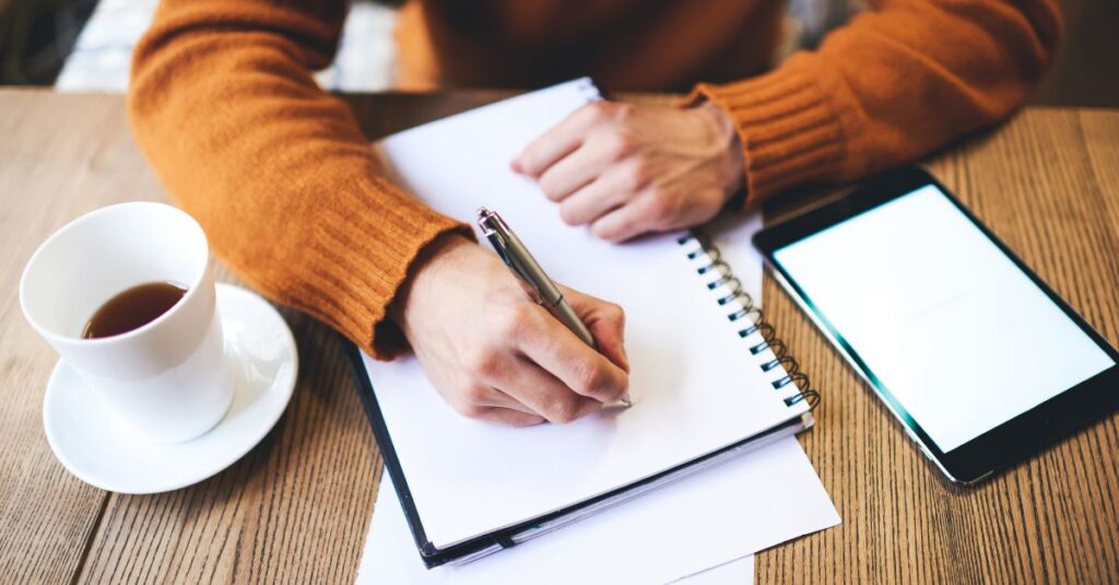 Man writing in his journal at his desk.