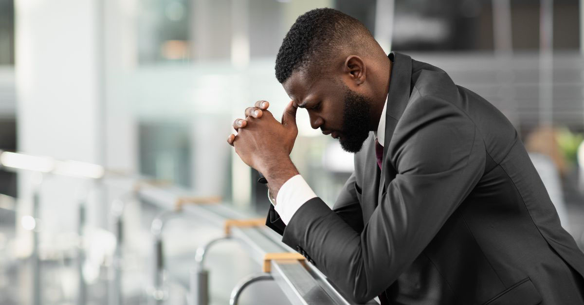 A frustrated man in a business suit takes a moment to gather himself as he overcomes stress.