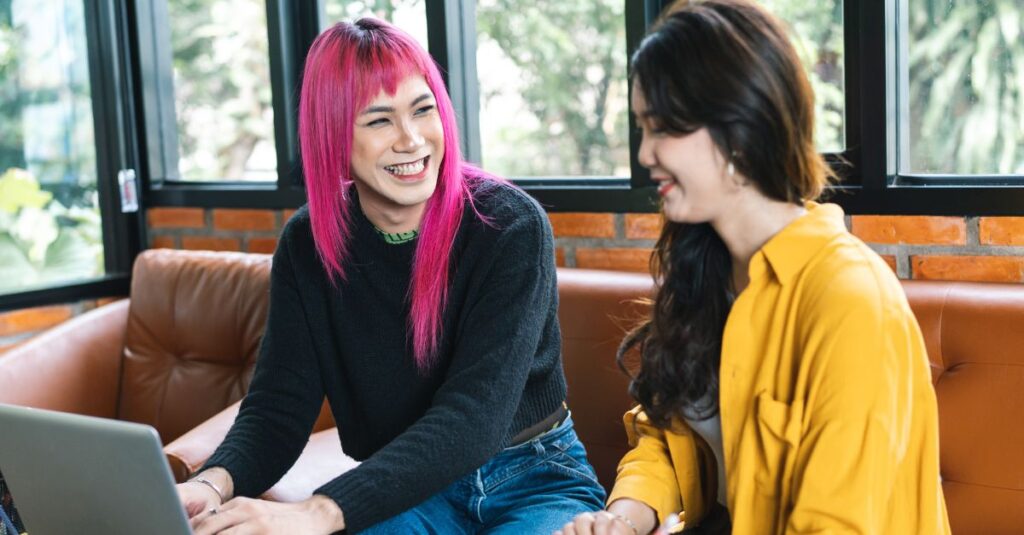 Transgender man sharing a laugh with a friend, symbolizing affirmation, confidence, and overall wellness.