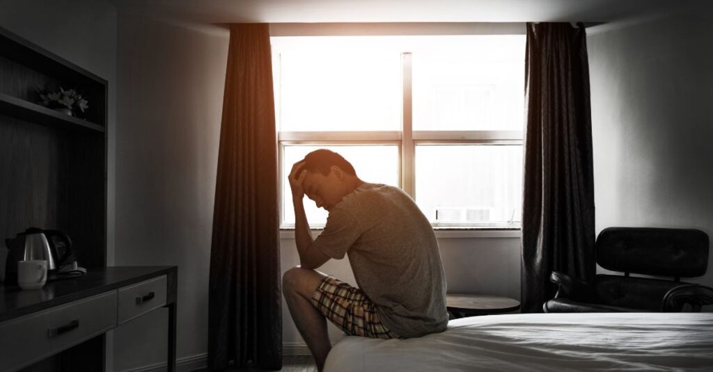 Stressed man experiencing nighttime anxiety and sleep disruption with racing thoughts