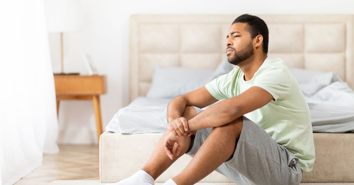 Thoughtful man in his 30s-40s sitting alone, natural lighting, contemplative expression, conveying introspection without distress