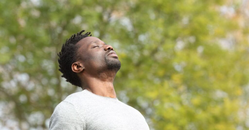 Man taking a breath of fresh outdoors, looking calm and relaxed.