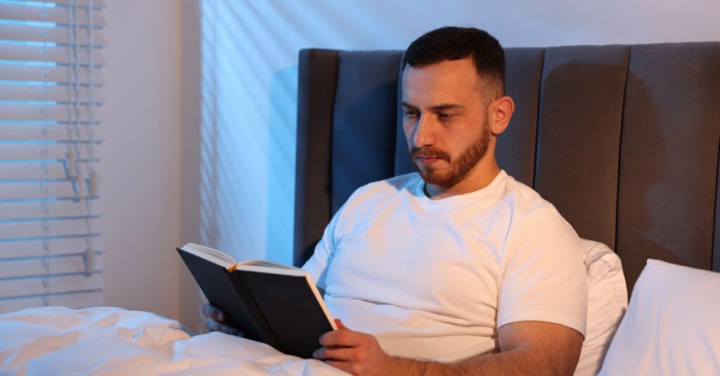 Man reading a book in dim/warm lighting in evening