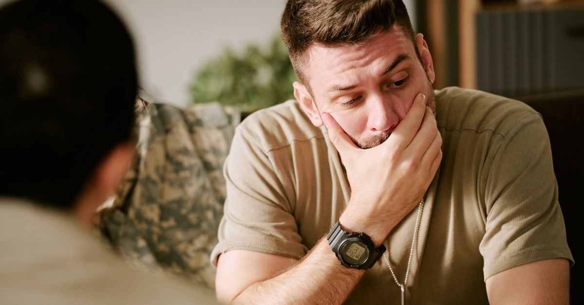 Veteran sits on a couch with a troubled look on his face.