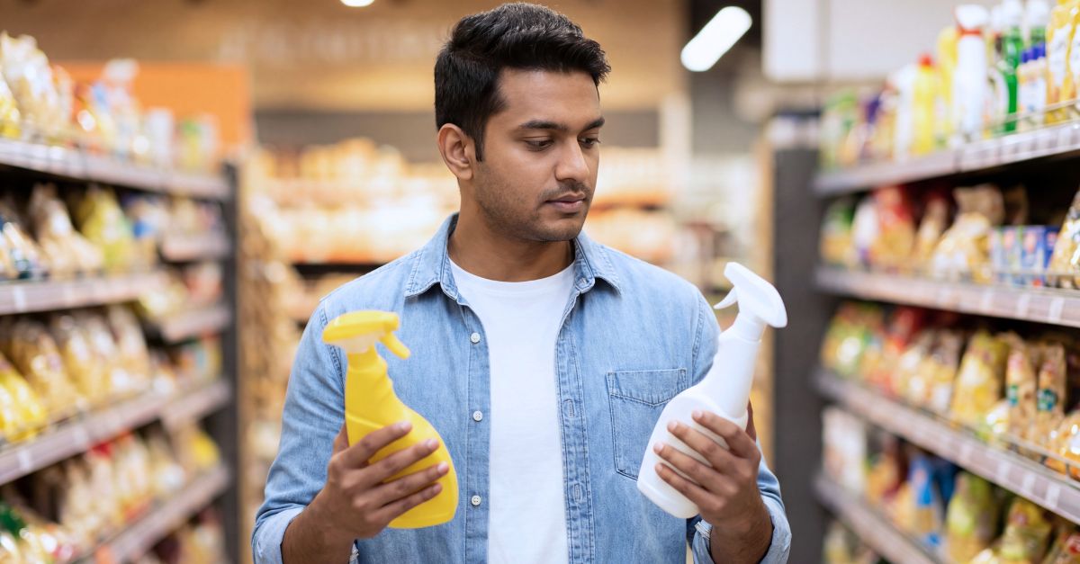 Man standing in a grocery store aisle comparing items.