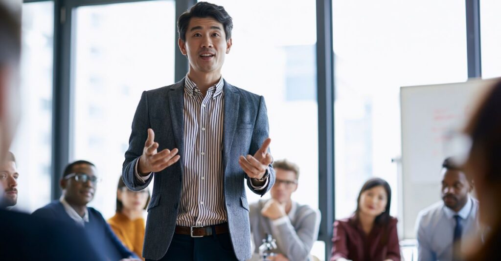 Man speaking confidently at a meeting in front of peers.